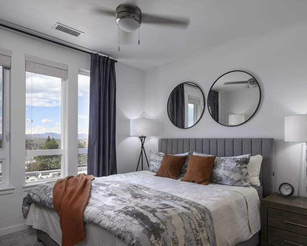 One Bedroom Luxury Apartments in Denver, CO - DECO Apartments Bedroom With Ceiling Fan, Stylish Decor, and Large Windows With Stunning Views